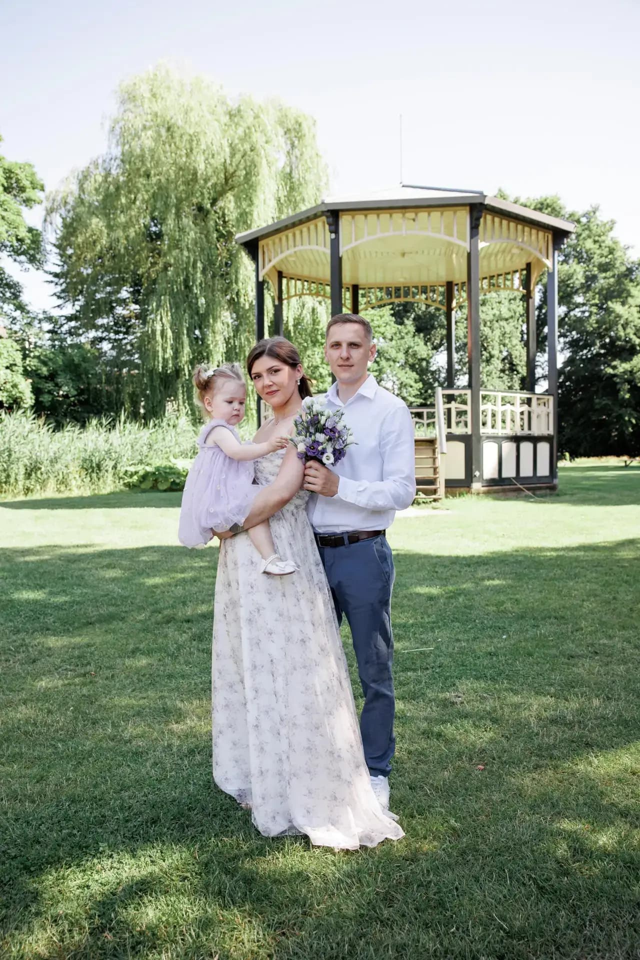 Groen licht, open gazons en een familie spelend onder de bomen.